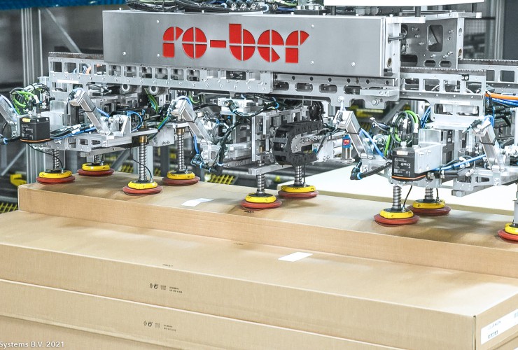 Along the hydraulic buffer aisle, four ro-ber FP150 series gantry robots pick pallets.